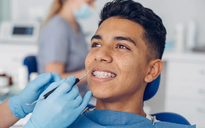 Joven sonriendo con brackets durante su control de ortodoncia