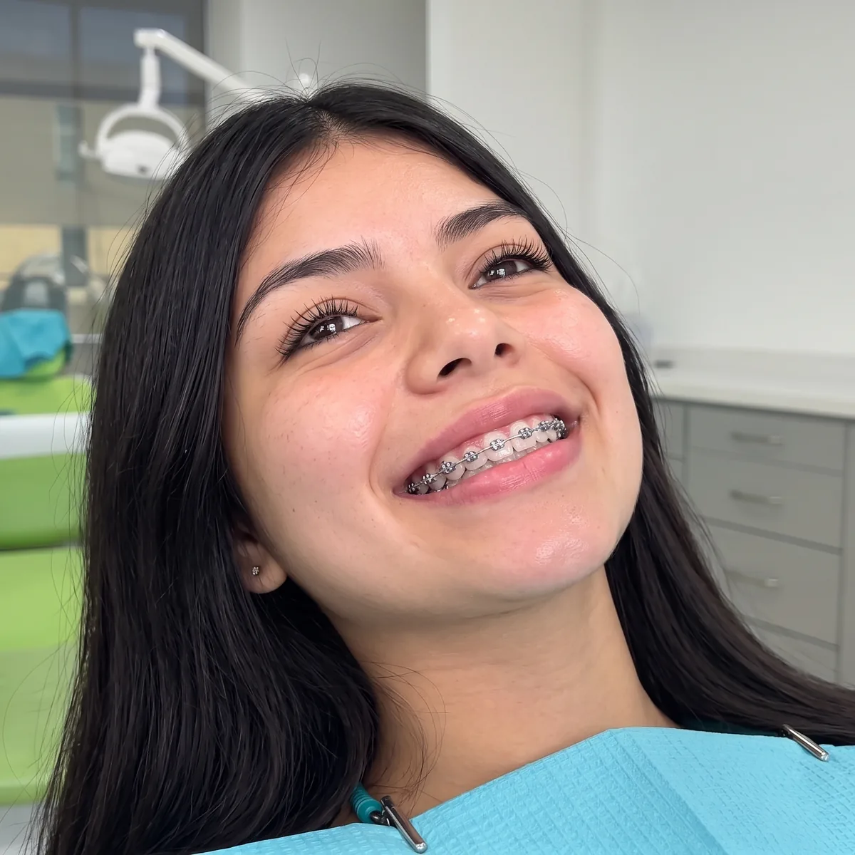 Joven sonriendo con brackets en el sillón del consultorio dental